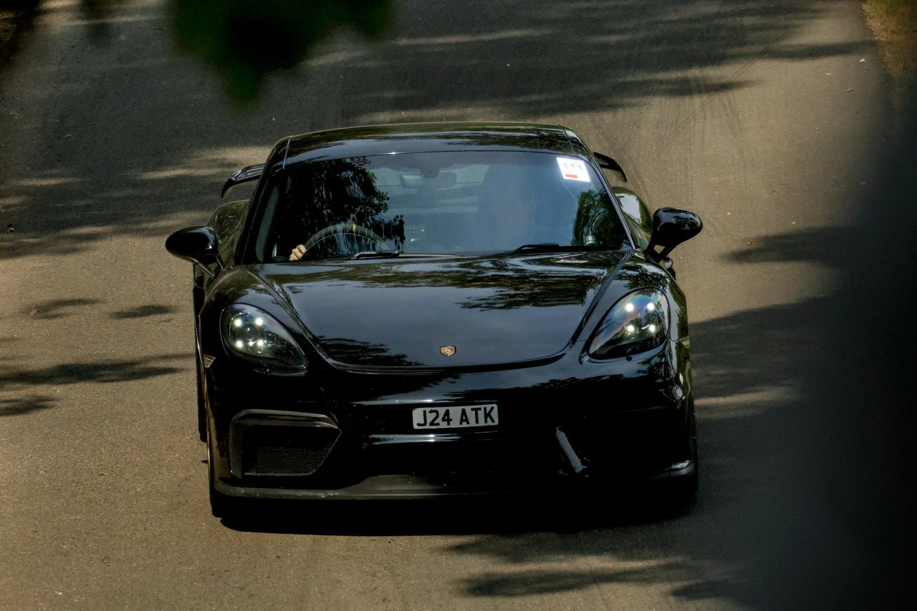 A dark Porsche on a tree-lined road, photographed by Louis Davis